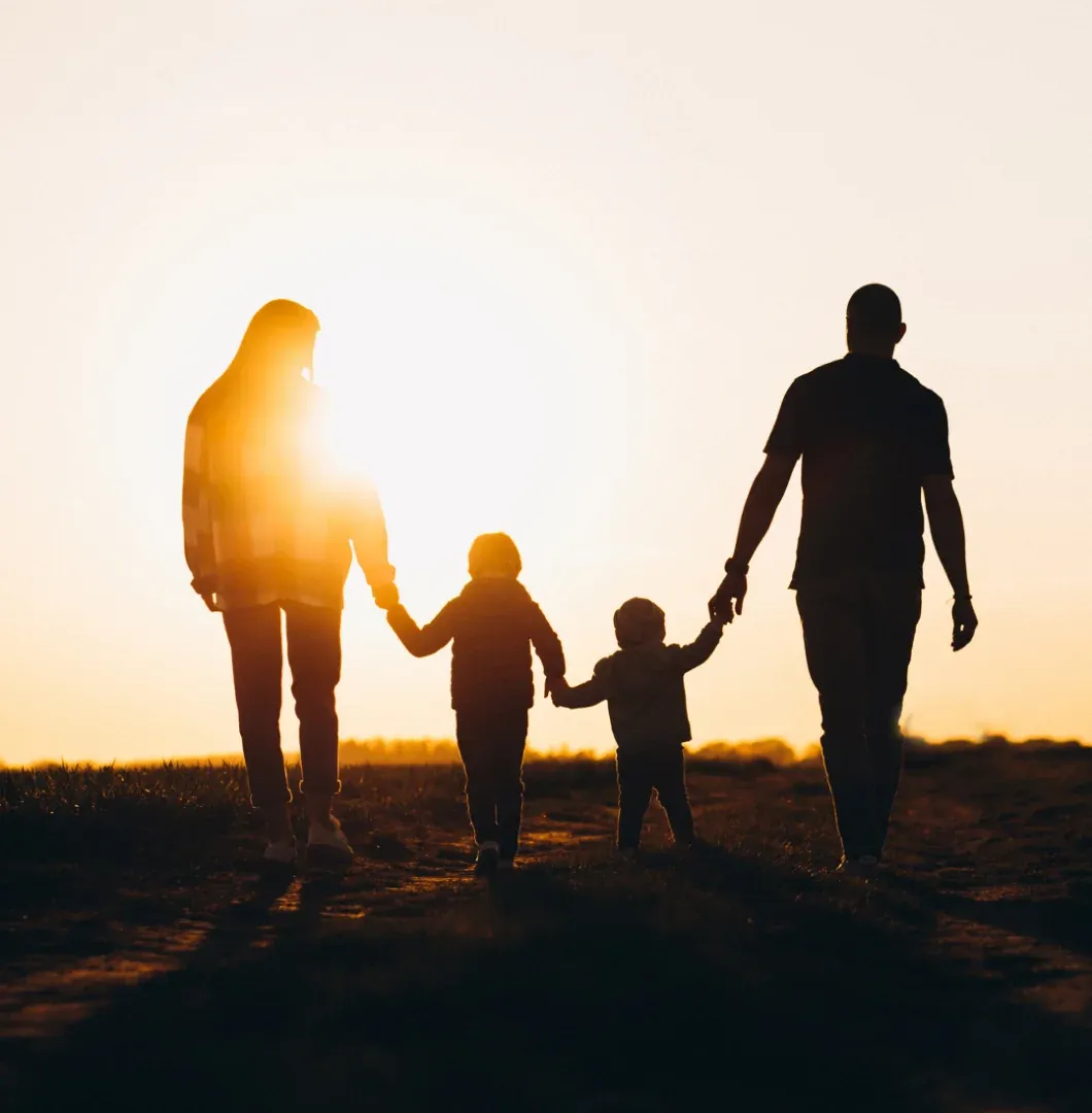 Família caminhando de mãos dadas ao pôr do sol
